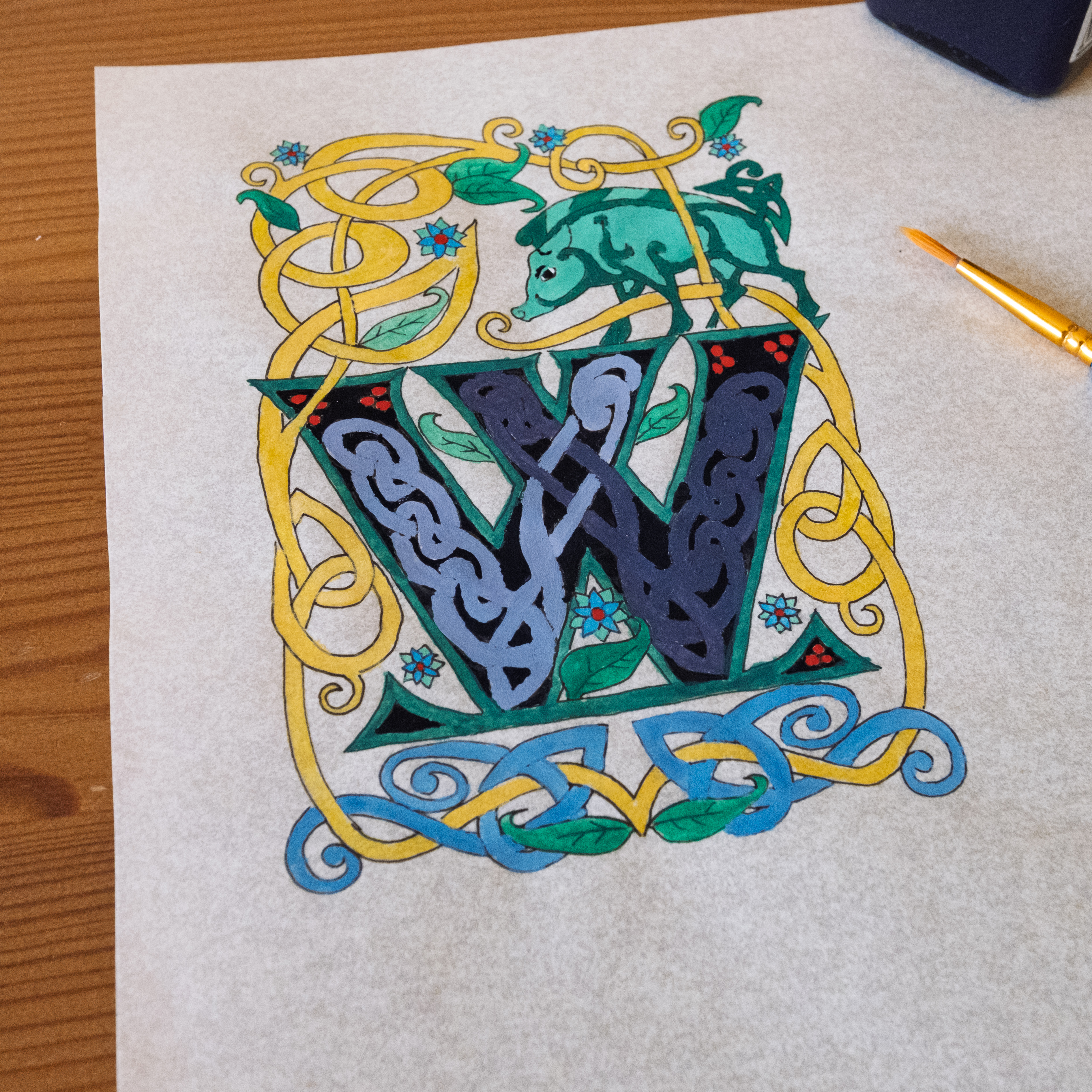 Illuminated initial W with green, gold, blue, and knotwork ornament